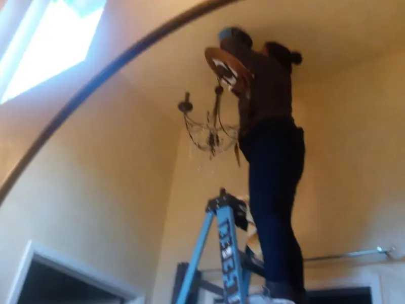 Electrician installing a chandelier in a Lyons residence